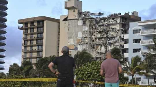 Ľudia sa pozerajú na časť zrútenej budovy v Miami na Floride.