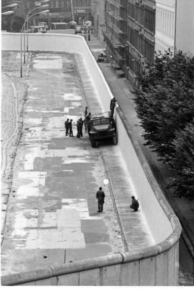 Na snímke z roku 1985 východonemeckí pohraničníci natierajú bielou farbou Berlínsky múr.