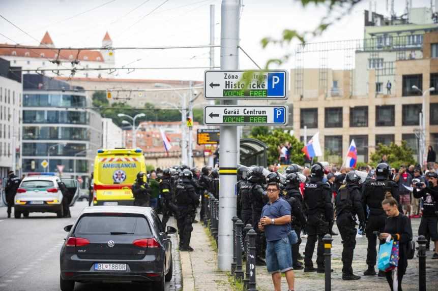 Policajní ťažkoodenci bránia protestujúcim v blokácii cesty.