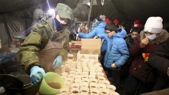 Migranti z Blízkeho východu a iných krajín, ktorí sa pokúšajú prekročiť hranice z Bieloruska do Poľska, stoja v rade na jedlo a teplé nápoje.