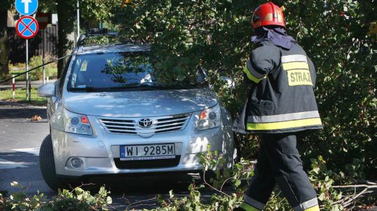 Hasiči odstraňujú z auta zaparkovaného mimo parkoviska konáre stromov, ktoré polámal silný vietor