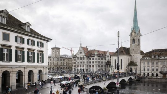 Ľudia stoja v rade na moste Münster pred miestnou radnicou počas hlasovania v referende o tzv. covidových pasoch v Zürichu.