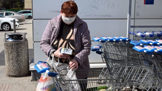 Na snímke seniorka si berie tašky z nákupného košíka.