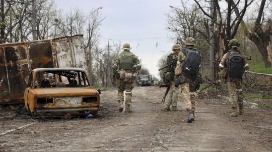 Príslušníci domobrany Doneckej ľudovej republiky kráčajú okolo vrakov áut počas bojov medzi ukrajinskou a ruskou armádou v obliehanom meste Mariupol.