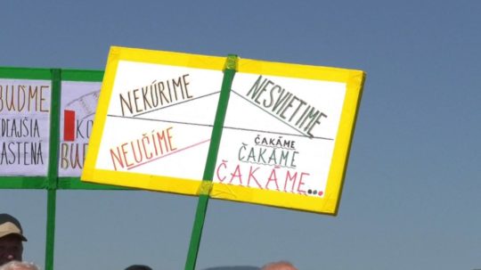 Na snímke protestujúci držia transparenty s nápismi.