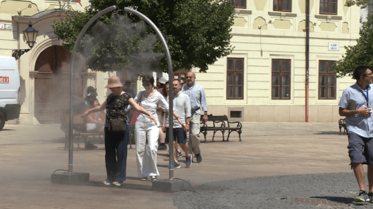 Na snímke sa nachádzajú ľudia prechádzajúci cez osviežujúci prúd vody.