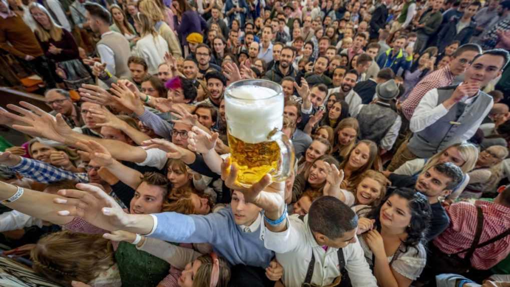 Mladí ľudia sa naťahujú za pivom zadarmo v jednom z pivných stánkov.