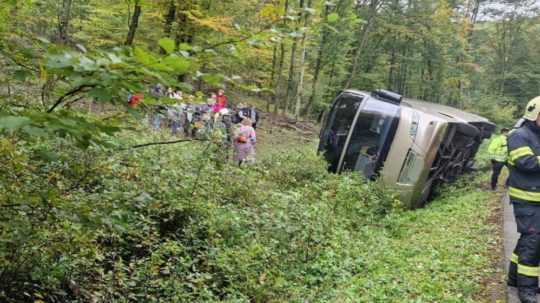 Na snímke je autobus mimo vozovky prevrátený nabok.