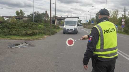 Policajt na hraničnom priechode zastavuje vozidlo.