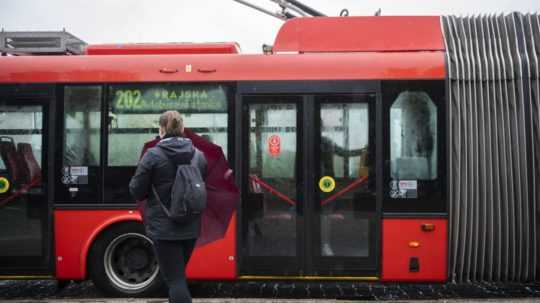 Na snímke žena s dáždnikom nastupuje do trolejbusu.