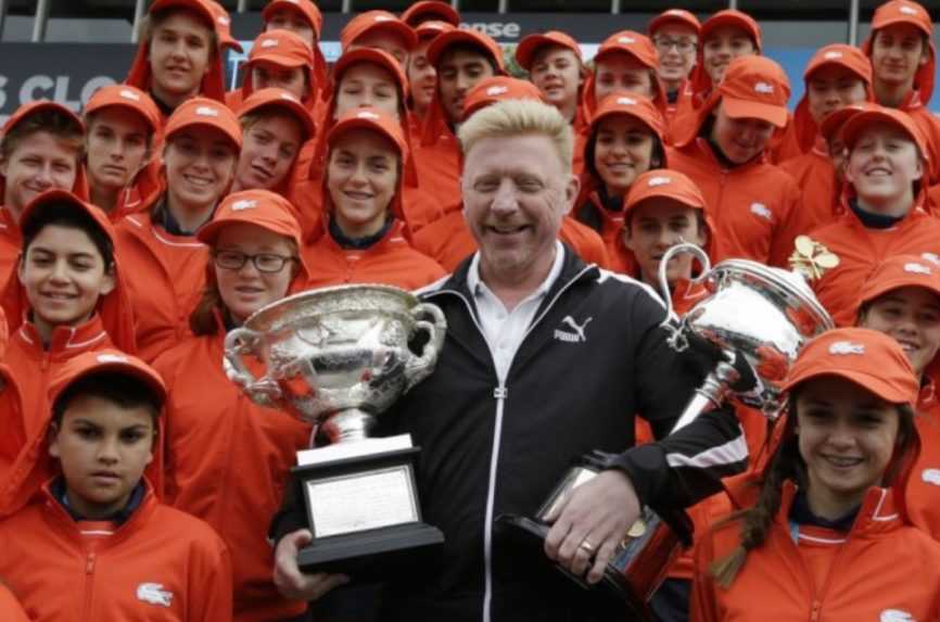 B&yacute;val&yacute; nemeck&yacute; tenista a v&iacute;ťaz Australian Open Boris Becker drž&iacute; trofeje pre v&iacute;ťazku ženskej dvojhry a v&iacute;ťaza mužskej dvojhry pred začiatkom z&aacute;pasov na &uacute;vodnom grandslame sez&oacute;ny Australian Open v Melbourne 19. janu&aacute;ra 2015.