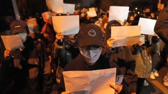 Protestujúci v Šanghaji držia prázdne papiere a pokrikujú slogany.