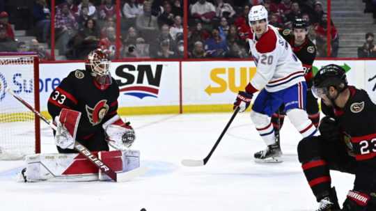 Na snímke druhý zľava slovenský útočník Canadiens Juraj Slafkovský, vľavo brankár Ottawy Cam Talbot, vpravo jeho spoluhráč v obrane Travis Hamonic v zápase zámorskej hokejovej NHL Ottawa Senators - Montreal Canadiens.