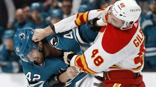 Jonah Gadjovich zo San Jose Sharks počas bitky s Dennisom Gilbertom z Calgary Flames.