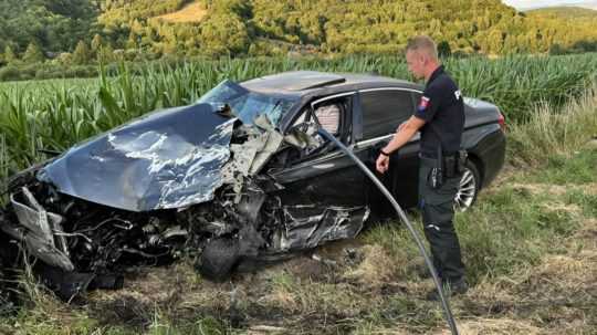 Policajt pred zdemolovaným autom.