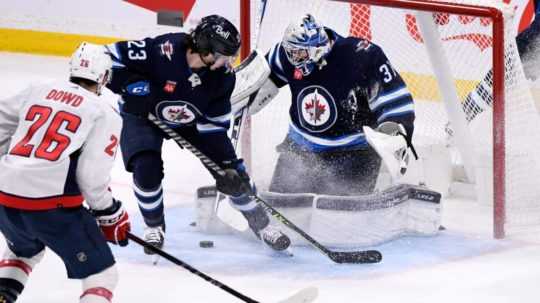 Na snímke brankár Winnipegu Connor Hellebuyck zneškodňuje strelu hráča Washingtonu Nica Dowda.