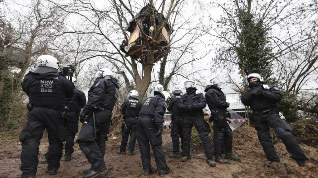 Policajti stoja v tábore klimatických aktivistov v dedine Lützerath.