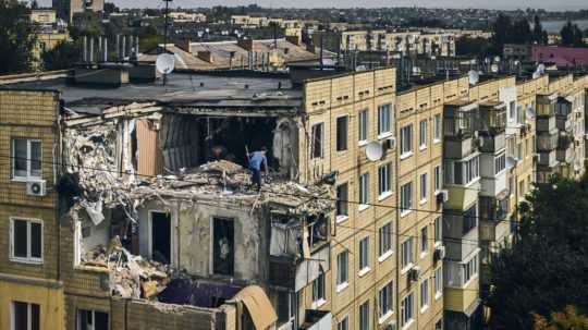 Na archívnej snímke muž upratuje interiér bytu zničeného po ruskom bombardovaní v meste Nikopol.