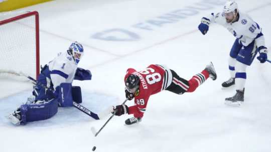 Na snímke vpravo slovenský obranca Tampy Erik Černák, uprostred hráč Chicaga Andreas Athanasiou a vľavo brankár Lightning Brian Elliott v zápase hokejovej NHL Chicago Blackhawks - Tampa Bay Lightning,