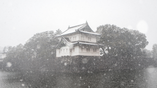 Na obrázku budova v typickej japonskej architektúre v zasneženej krajine.