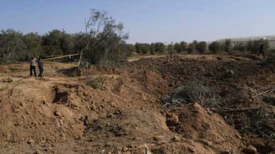 a snímke ľudia sledujú jamu v zemi a zničené olivové stromy vo vojenskom tábore hnutia Hamas, ktorý sa nachádza v utečeneckom tábore Maghazi v pásme Gazy 4. novembra 2022.