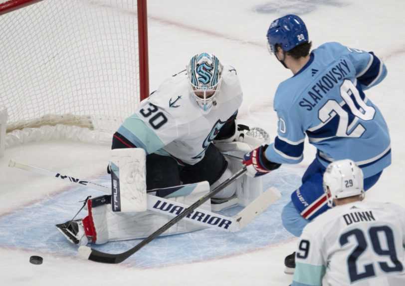 Slovenský útočník Juraj Slafkovský v drese Montrealu Canadiens strieľa na brankára Seattlu Krakens Martina Jonesa.