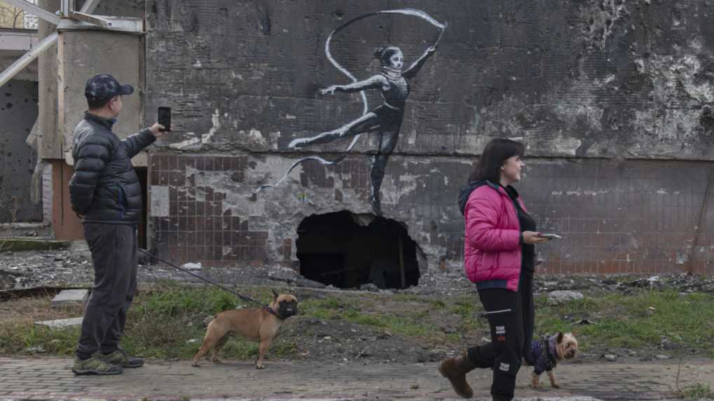 Dielo zobrazuje gymnastku s fixačným golierom na krku mávajúcu stuhou na budove poškodenej ostreľovaním v ukrajinskom meste Irpiň.