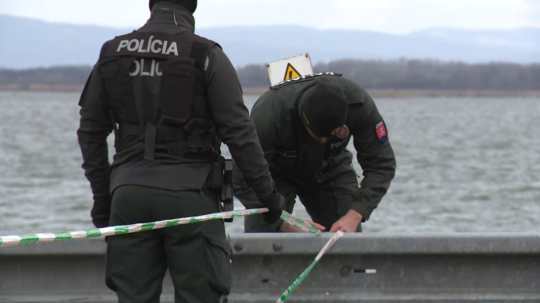 Policajní príslušníci zaisťujú priestory pri vodnom diele páskou.