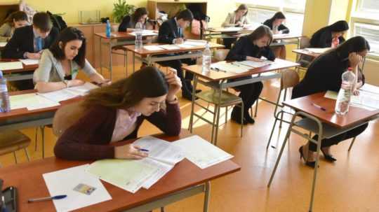 na snímke študenti sedia v laviciach a píšu maturitné testy