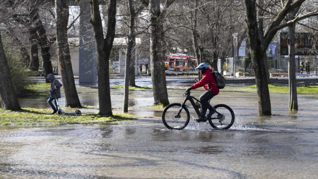 Cyklista jazdí cez zaplavenú časť Sadu Janka Kráľa v Bratislave.