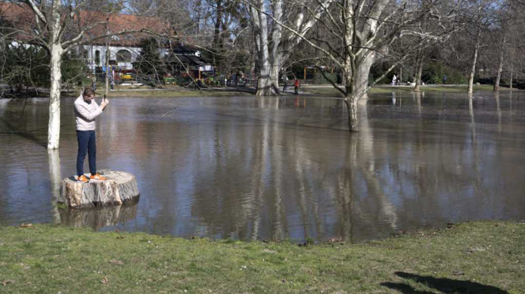 Muž stojí na kameni a fotí mobilným telefónom zaplavenú časť Sadu Janka Kráľa v Bratislave.