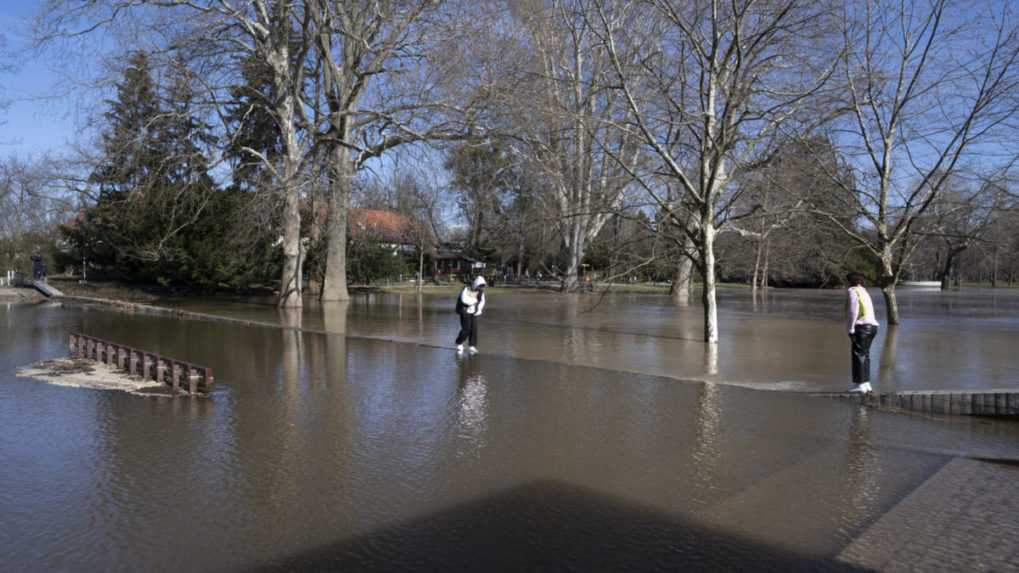 Na snímke sa dve osoby snažia prejsť zaplaveným sadom Janka Kráľa.