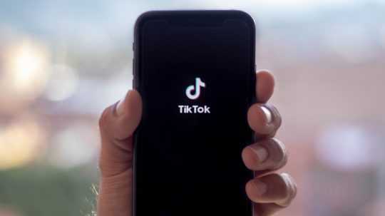 muž drží mobil s aplikáciou TikTok