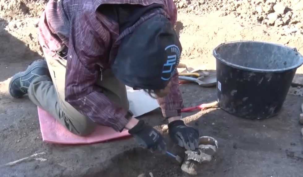 archeologička čistí nájdenú ľudskú kostru