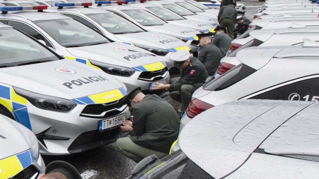 Na snímke policajti kľučia pri svojich nových autách