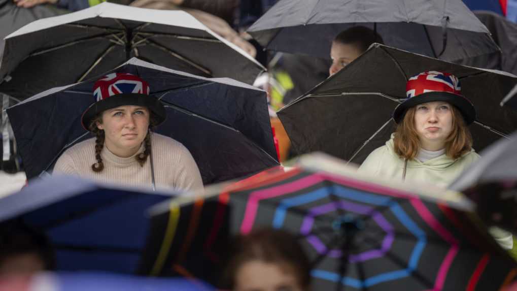 Fanúšikovia kráľovskej rodiny sedia pod dáždnikmi pred slávnostnou korunováciou britského kráľa Karola III. a jeho manželky Kamily v Hyde parku.