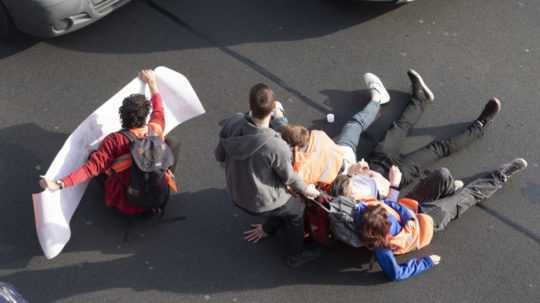 Muž sa snaží z cesty odtiahnuť protestujúcich.