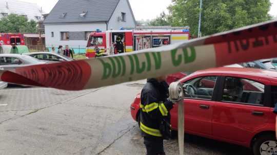 na snímke v popredí policajná páska za ňou hasičské auto a hasiči