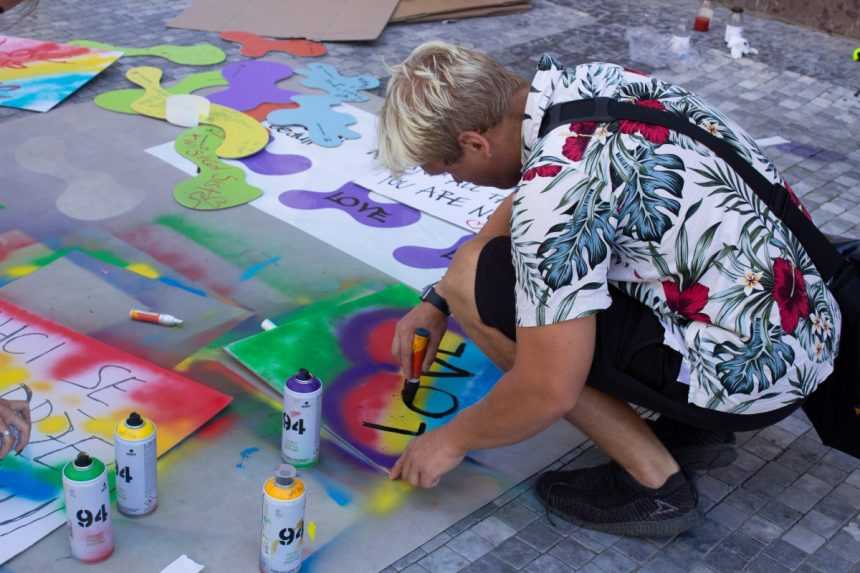 Účastník si pred začiatkom pochodu Prague Pride 2023 pripravuje transparent.