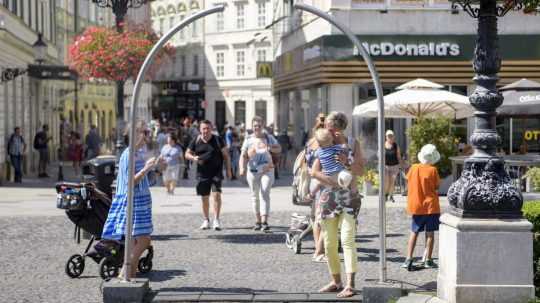 Ľudia prechádzajú pod oblúkom, ktorý rozprašuje vodu.