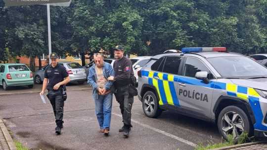 Na snímke polícia sprevádza nebezpečného muža.