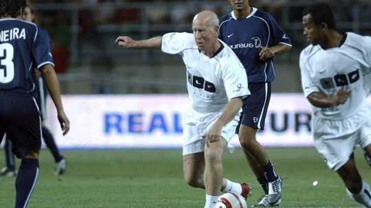 Bobby Charlton (uprostred), hrajúci za tím nadácie Luisa Figa, vyzýva hráčov nadácie Laureus Marca Caneiru (vľavo) a Daniho (v pozadí).