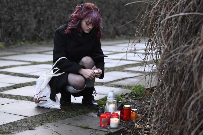 Mláda žena zapaľuje sviečku na námestí Jana Palacha neďaleko FF UK.