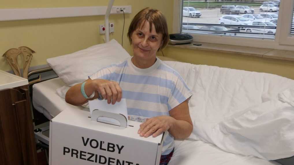 Na sn&iacute;mke volička vhadzuje ob&aacute;lku s hlasovac&iacute;m l&iacute;stkom do prenosnej volebnej schr&aacute;nky.