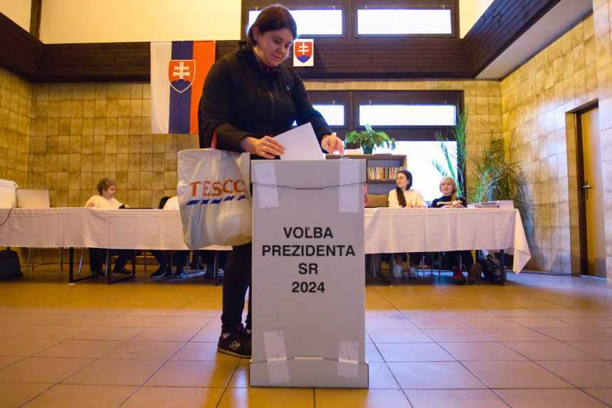 Na sn&iacute;mke žena vhadzuje ob&aacute;lku s hlasovac&iacute;m l&iacute;stkom do volebnej schr&aacute;nky v budove železničnej stanice v meste Kr&aacute;sno nad Kysucou v okrese Čadca.