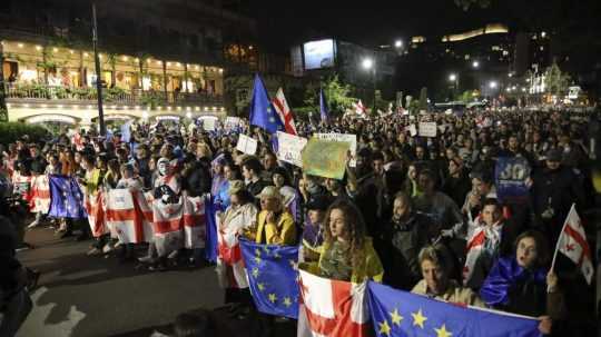 Demonštranti s gruzínskymi štátnymi vlajkami a vlajkami EÚ pochodujú počas opozičného protestu proti "ruskému zákonu" v centre gruzínskeho Tbilisi v piatok 3. mája 2024.