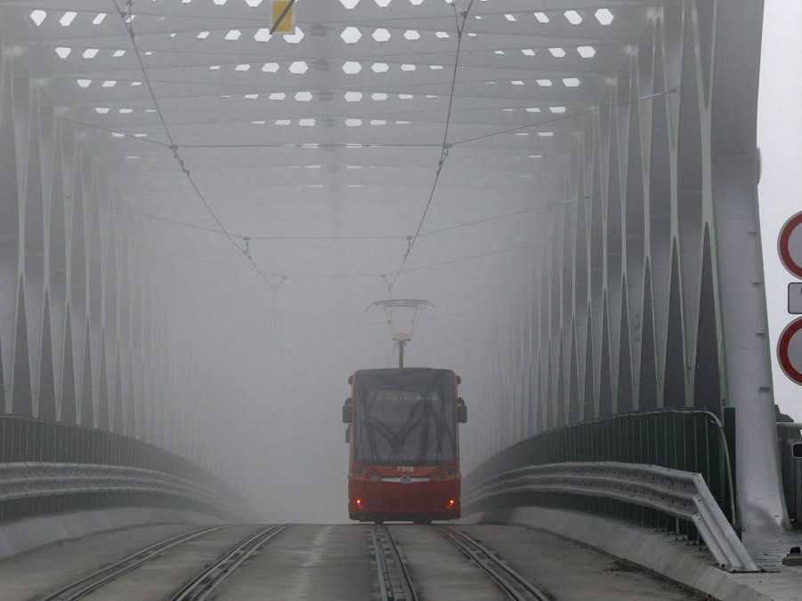 Električka jazdí po Starom moste počas hmlistého počasia v Bratislave.