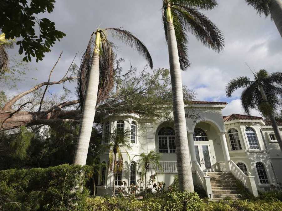 Vyvrátený strom leží na vrchole domu v meste Siesta Key na Floride.