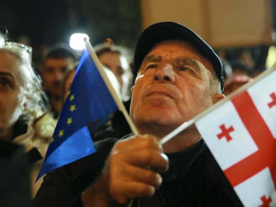 Muž drží vlajky EÚ a Gruzínska.