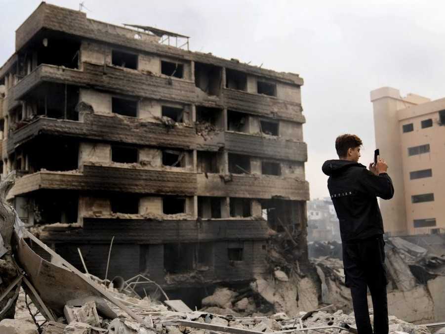 Ilustračná snímka - muž fotí zničenú budovu po leteckom útoku izraelskej armády na predmestí Dáhíja na juhu Bejrútu v Libanone.